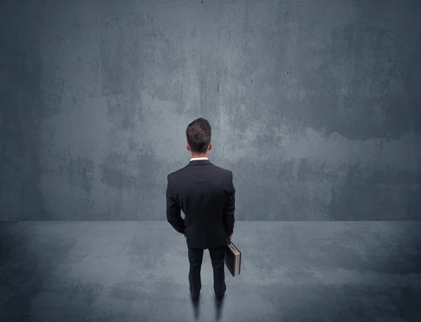 Businessman standing in front of urban wall — Stock Photo, Image