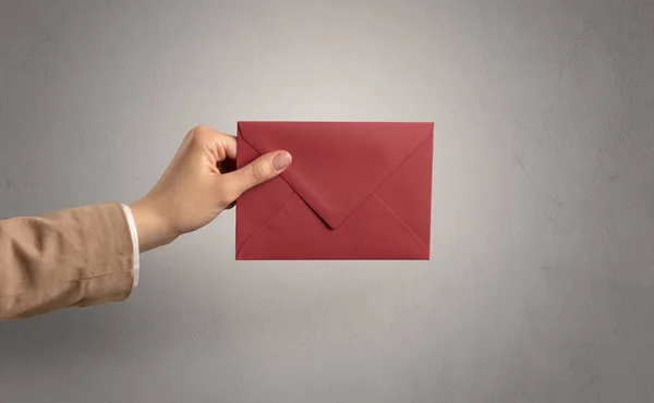 Hand holding envelope with empty wall background — Stock Photo, Image