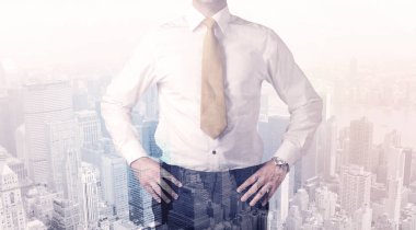 İş adamı çatıda duruyor ve arka planda şehir var.