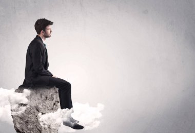 Ofis çalışanı kayanın tepesinde oturuyor.