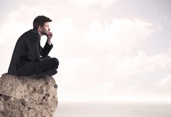 Business man sitting on stone edge — Stock Photo, Image