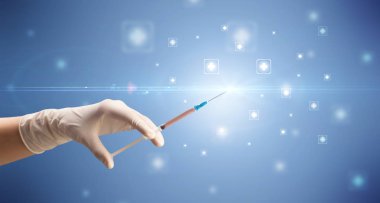 Kadın doktor elinde şırınga tutuyor.