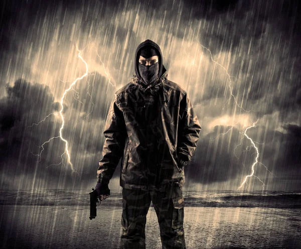 Gefährlicher bewaffneter Terrorist mit Maske und Waffe im Gewitter — Stockfoto