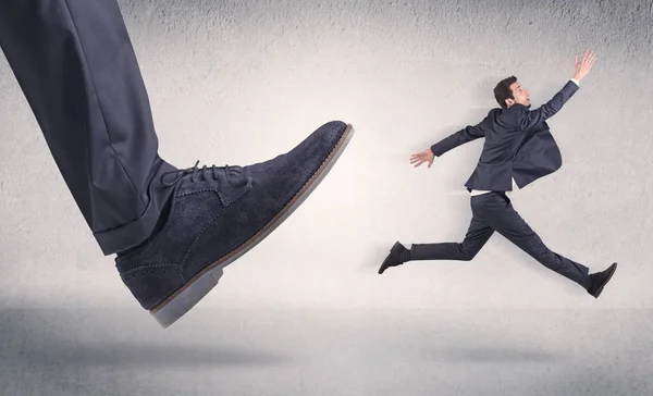 Small businessman kicked by big shoe — Stock Photo, Image