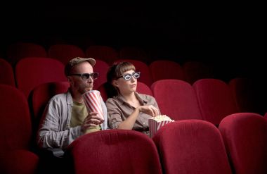 Genç çift kırmızı sinemada oturuyor