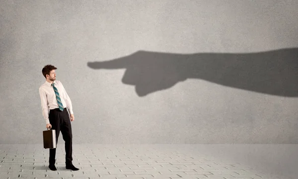 Business person looking at huge shadow hand pointing at him concept — Stock Photo, Image