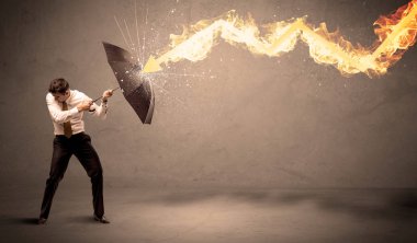 İş adamı kendini bir umbrell ile bir yangın oka savunmak