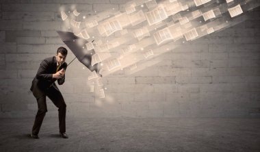 İş adamı ile şemsiye kağıtları rüzgara karşı koruma