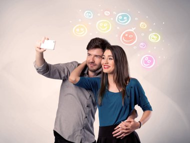 Mutlu çift gülen yüzle selfie çekiyor.