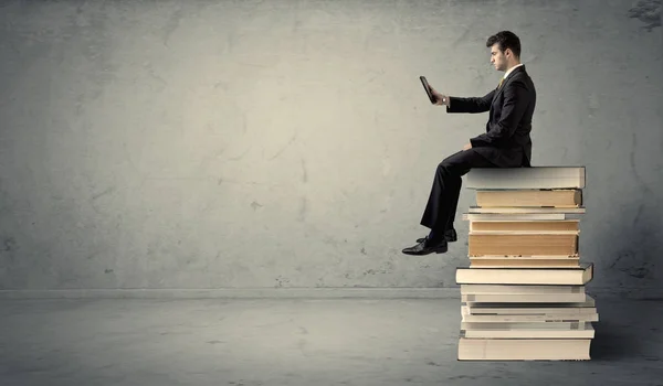 Man met laptop zitting op boeken — Stockfoto