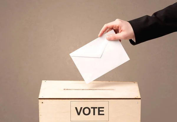 Close up of male hand putting vote into a ballot box