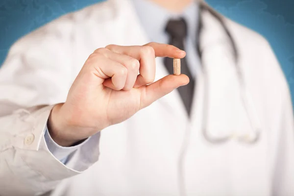 Doctor in white holding a pill — Stock Photo, Image