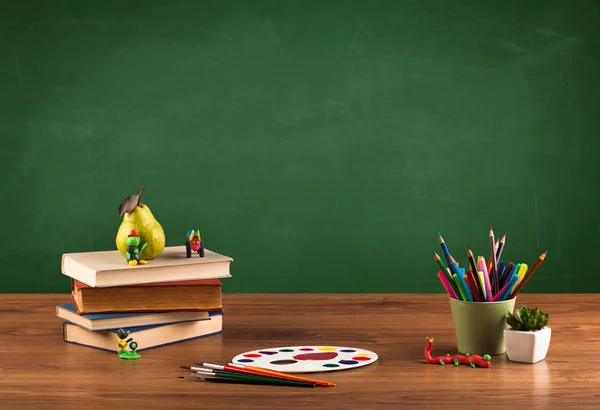 Przedmioty szkolne na biurku z pustą tablicą — Zdjęcie stockowe