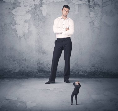 Büyük işletme zorbası küçük iş arkadaşına bakıyor.