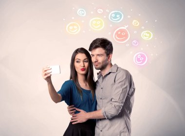 Mutlu çift gülen yüzle selfie çekiyor.