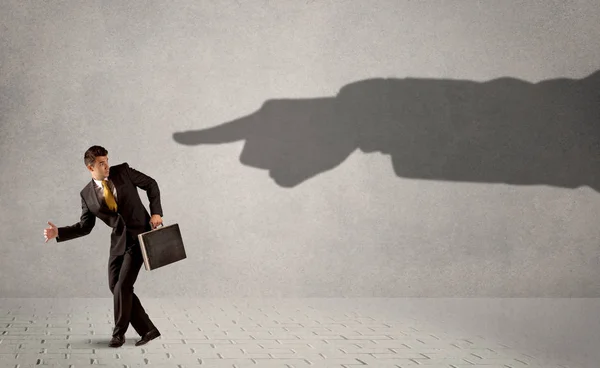 Business person looking at huge shadow hand pointing at him concept — Stock Photo, Image