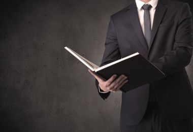 Elinde kitap tutan bir işadamı.