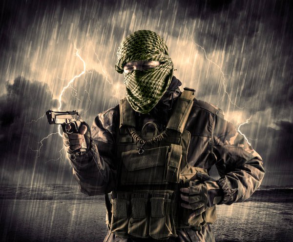 Dangerous armed terrorist with mask and gun in a thunderstorm wi
