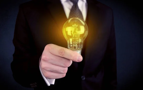Man in suit holding a glowing yellow light bulb — Stock Photo, Image