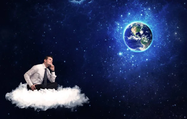 Человек, сидящий на облаке, глядя на планету Земля — стоковое фото