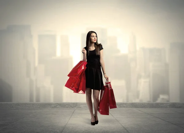 Κομψό κορίτσι της πόλης με κόκκινες τσάντες για ψώνια — Φωτογραφία Αρχείου