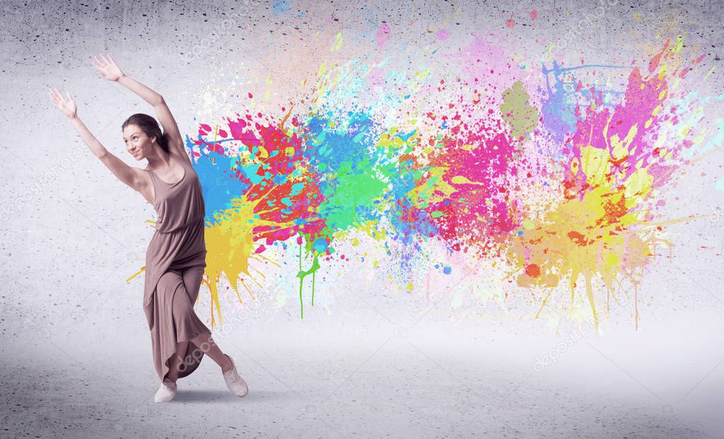 Modern street dancer jumping with colorful paint splashes