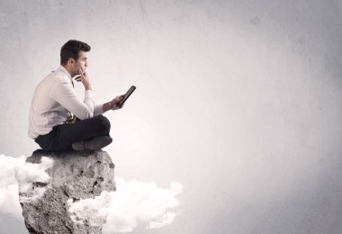 Ofis çalışanı kayanın tepesinde oturuyor.