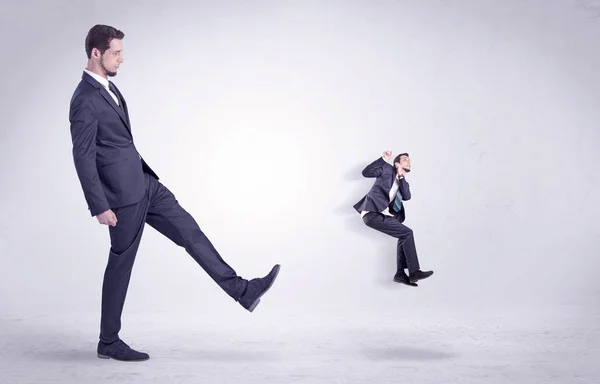 Gran hombre pateando poco a sí mismo fuera — Foto de Stock