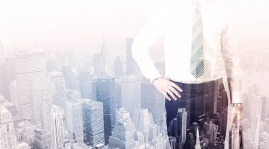 İş adamı çatıda duruyor ve arka planda şehir var.