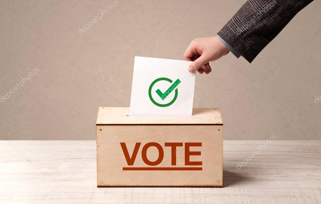 Close up of male hand putting vote into a ballot box