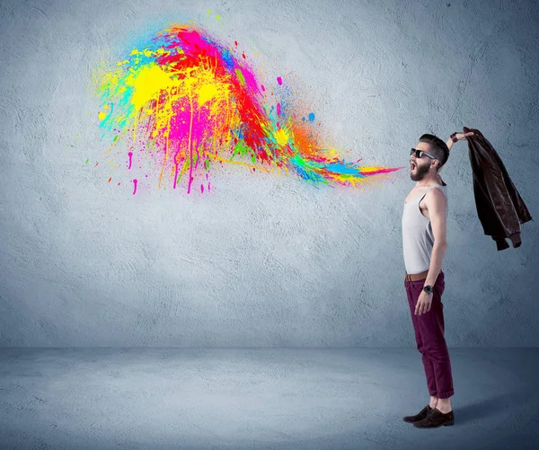 Hipster guy shouting colorful paint on wall — Stock Photo, Image