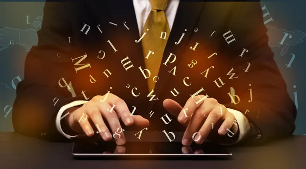 Man typing in formal clothing and letters around