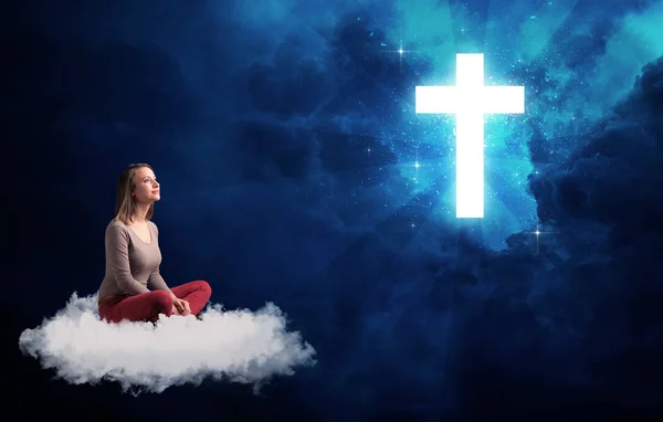 Woman sitting on a cloud looking at a cross — Stock Photo, Image