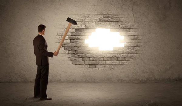 Business man hitting brick wall with hammer and opening a hole — Stock Photo, Image