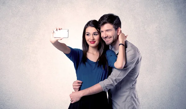 Casal feliz tomando selfie com parede clara — Fotografia de Stock