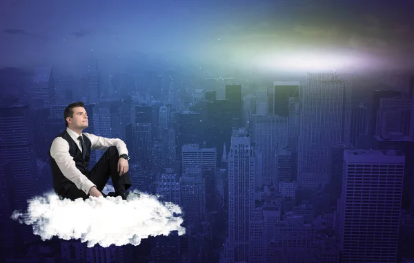 Şehrin yukarısındaki bir bulutun üzerinde oturan adam — Stok fotoğraf