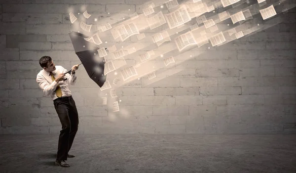 Hombre de negocios protegiendo con paraguas contra viento de papeles — Foto de Stock