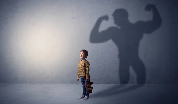 Muscleman shadow behind waggish little boy — Stock Photo, Image