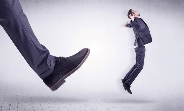 Young worker kicked out by big foot — Stock Photo, Image