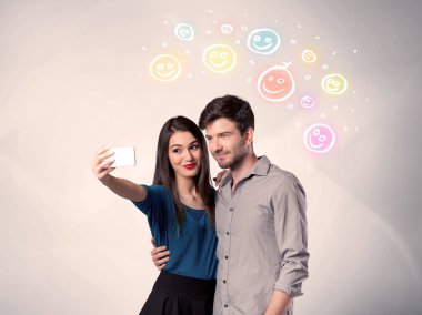 Mutlu çift gülen yüzle selfie çekiyor.