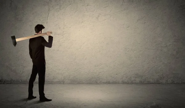 Hombre de negocios de pie frente a una pared grumosa con un martillo —  Fotos de Stock