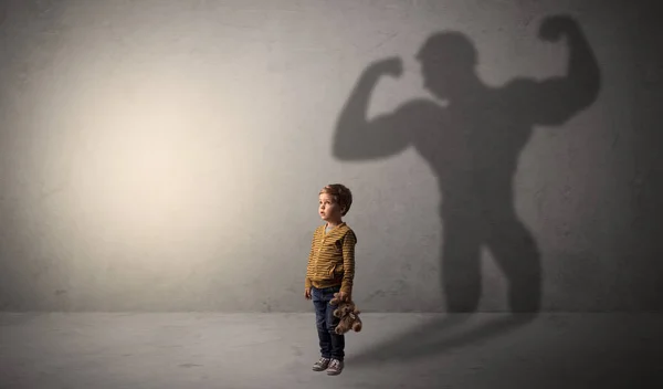 Muscleman shadow behind waggish little boy — Stock Photo, Image