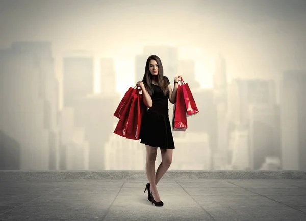 Elegante chica de ciudad con bolsas de compras rojas —  Fotos de Stock