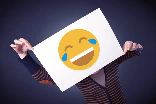 Жінка тримає папір зі сміховинним емоційок — стокове фото