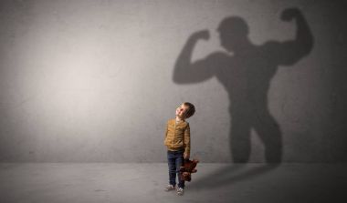 Waggish küçük çocuk arkasında muscleman gölge