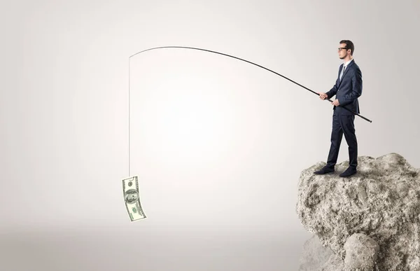 Businessman fishing dollar from a rock — Stock Photo, Image