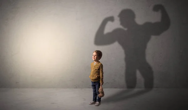 Muscleman shadow behind waggish little boy — Stock Photo, Image