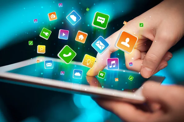 Hand using tablet with application icons flying around — Stock Photo, Image
