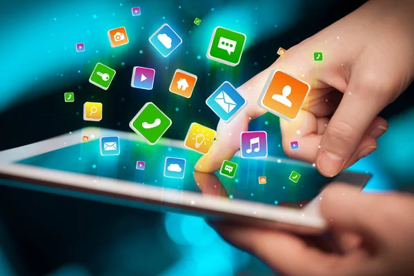 Main en utilisant une tablette avec des icônes d'application volant autour — Photo