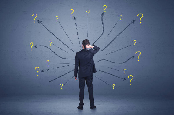 Бизнесмен, стоящий на переднем крае и знаков вопроса концепция
